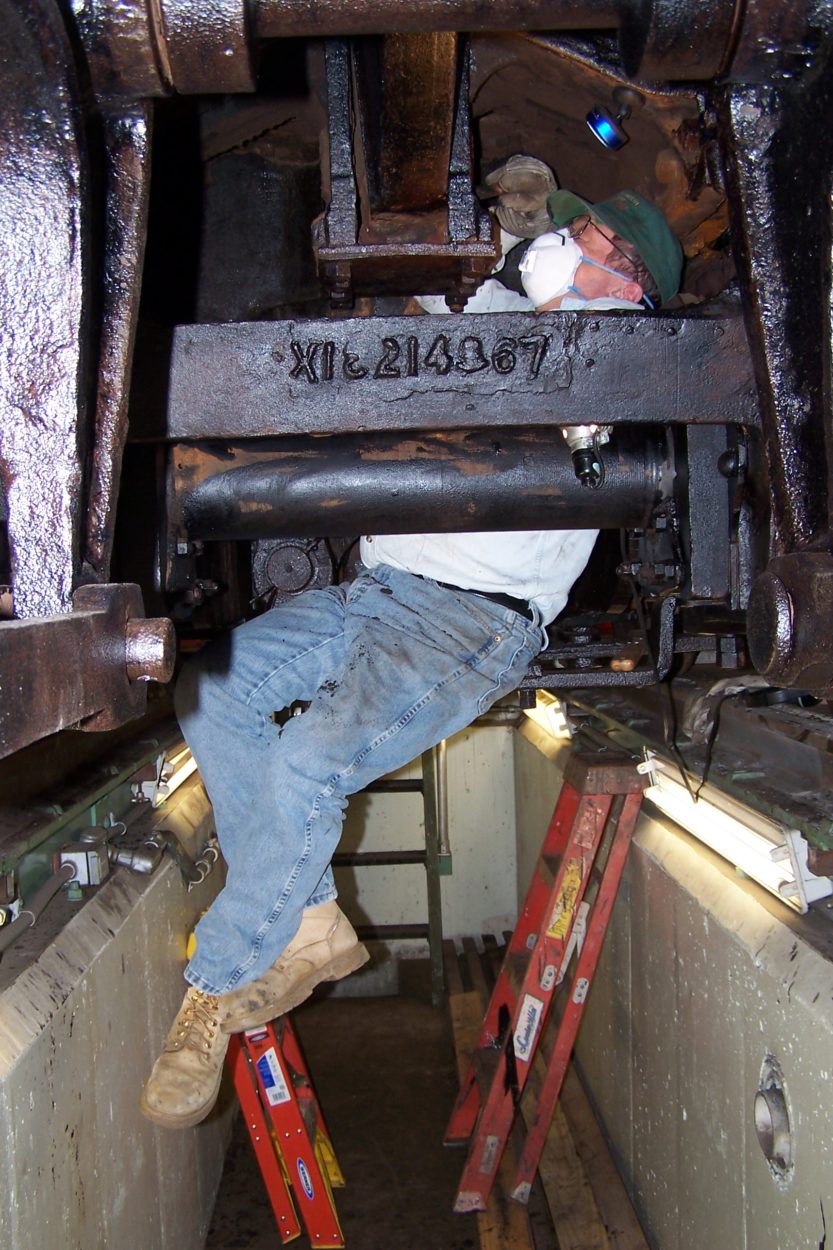 Man working inside of a floor trench underneath of a locomotive