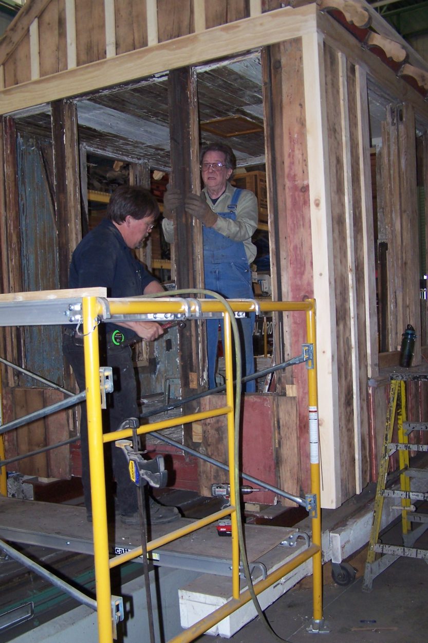 Two workers adding a door to a wood framed structure