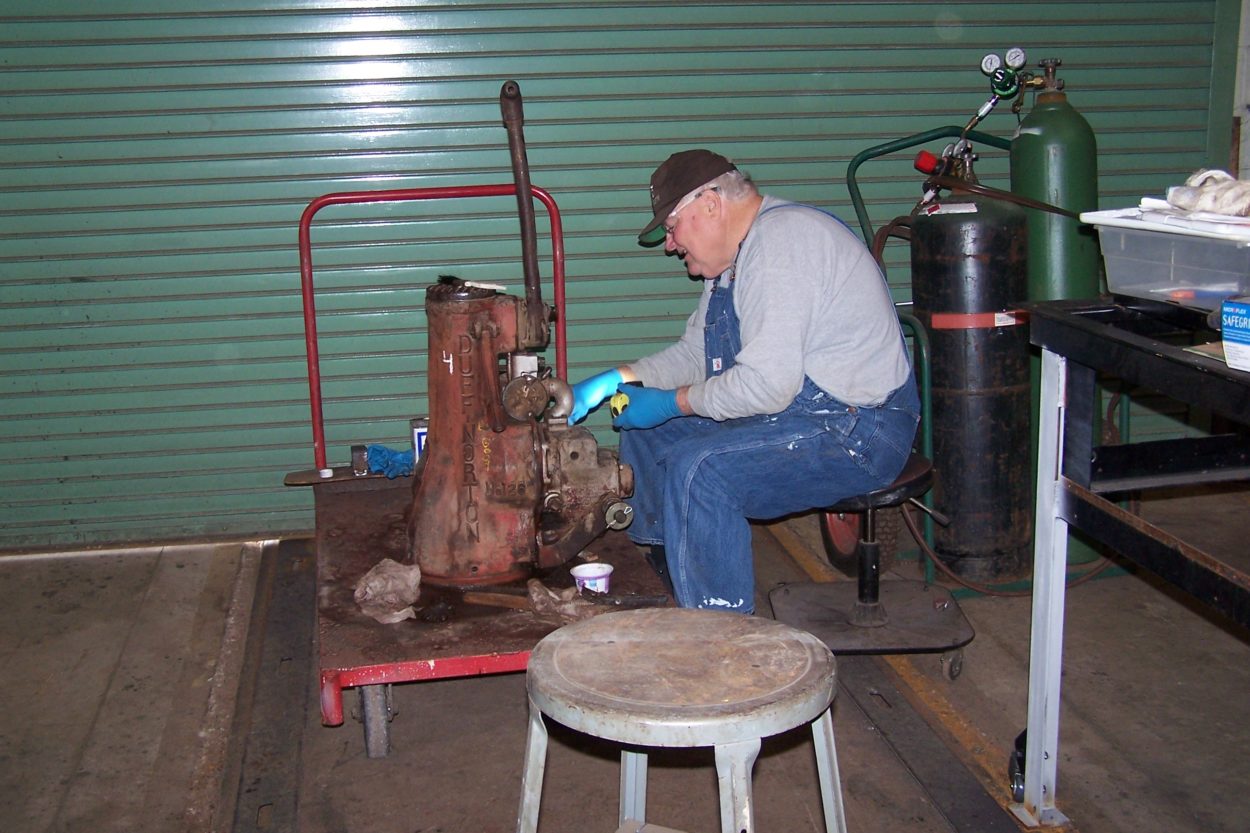 A man disassembling a piece of machinery from a locomotive for restoration