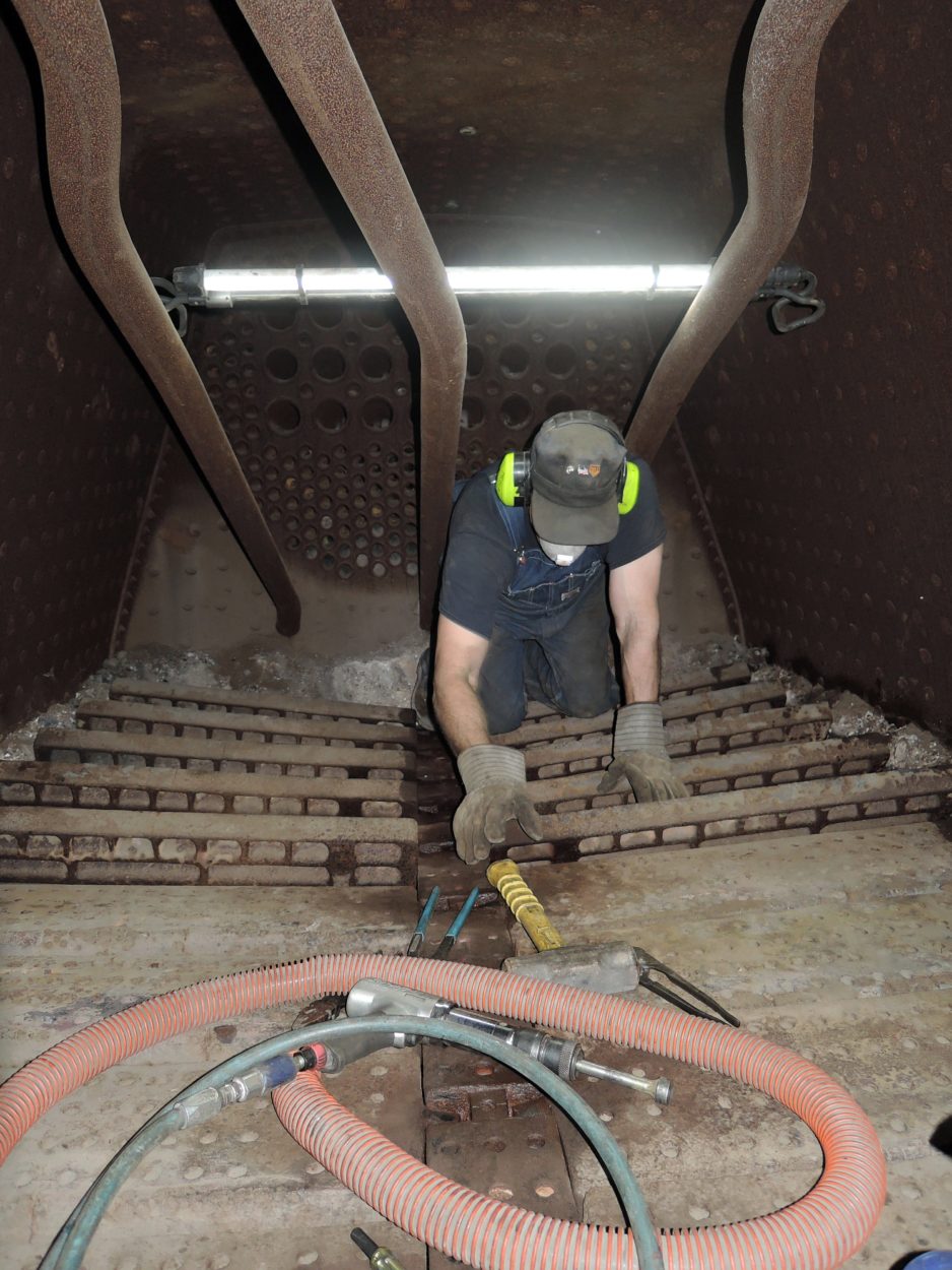 Worker inside of a locomotive boiler repairing damage