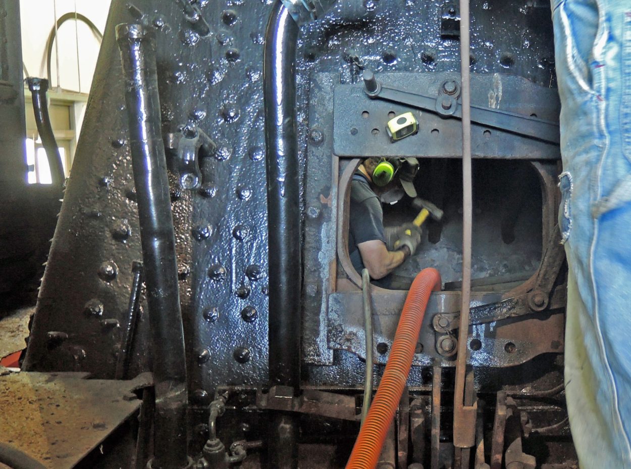 View of a worker through the firebox door working in the boiler