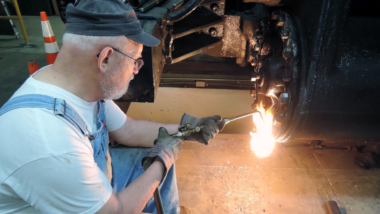 worker using a torch cutter while working on a restoration piece