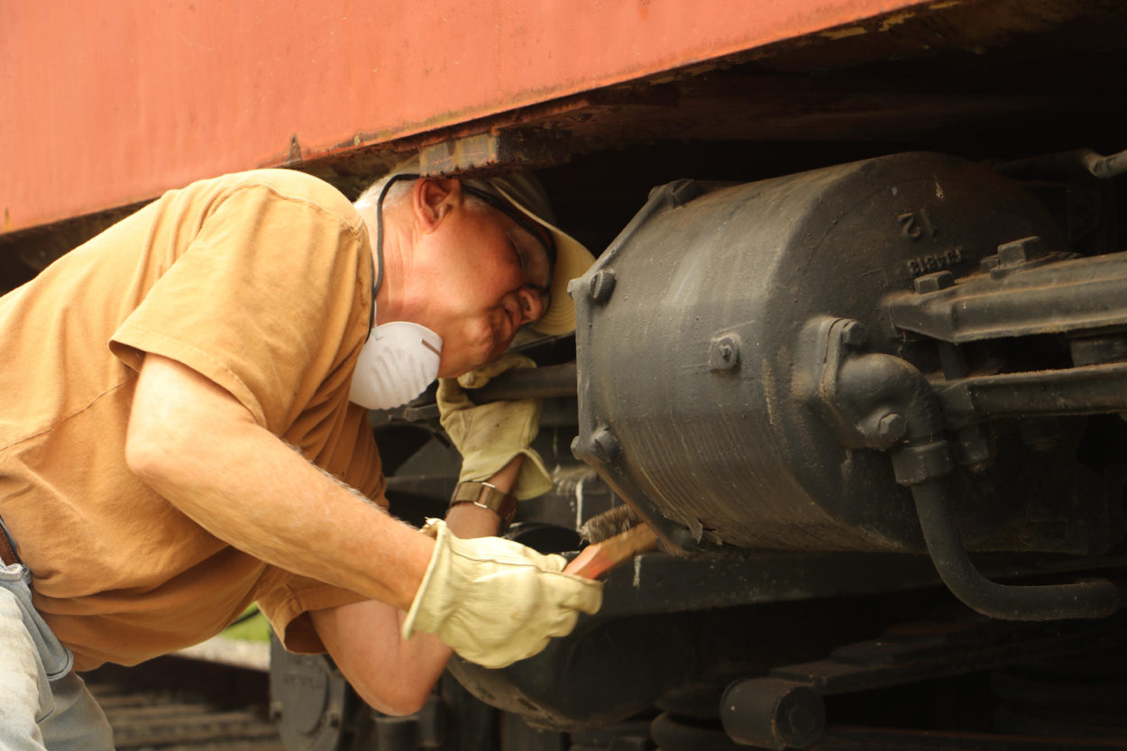 Worker cleaning a locomotive with a steel brush