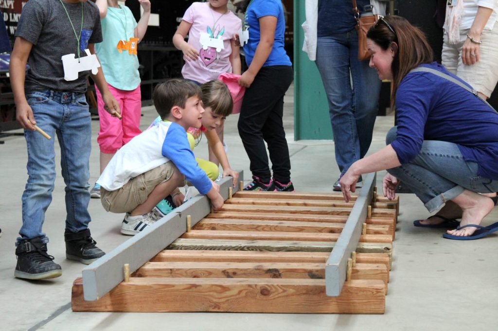 Kids building scale-size railroad tracks as part of a museum tour.